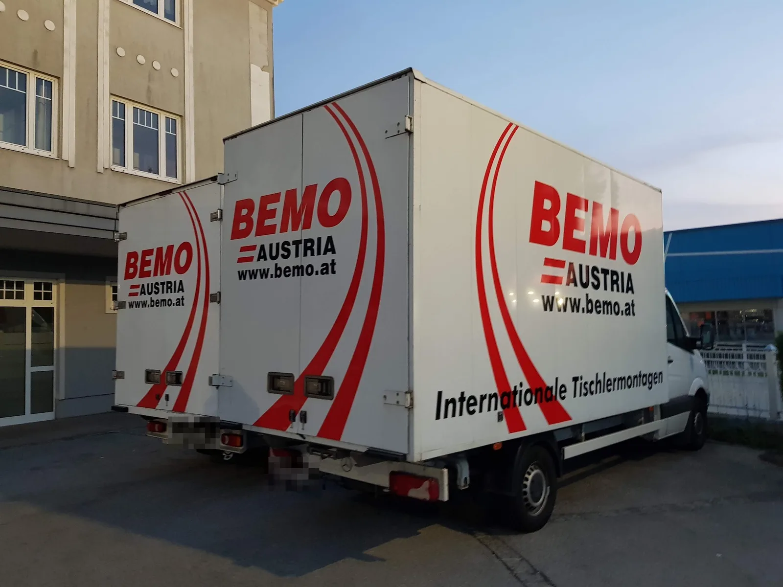 Zwei weiße BEMO-Koffer-LKW mit roten Schwüngen, von hinten gesehen